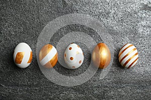 Set of traditional Easter eggs decorated with golden paint on grey background