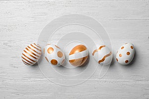 Set of traditional Easter eggs decorated with golden paint on wooden background