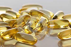 Set of transparent yellow capsules with omega-3 on a gray background.