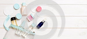 Set of travel size cosmetic bottles on white wooden table background. Flat lay of cream jars. Top view of bodycare style concept