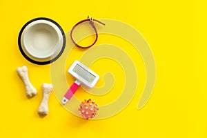 Set of treats and toys for pets with bones, collar and bowl on yellow background top view frame space for text