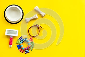 Set of treats and toys for pets with bones, collar and bowl on yellow background top view frame space for text