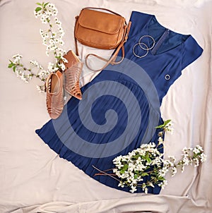 Set of trendy female clothes, accessories and blossoming branches on fabric background, flat lay