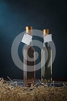 Set of two 250 ml bottles of white and pink wine with blank labels. Wooden shavings below. Wines assortment. Copy space, vertical