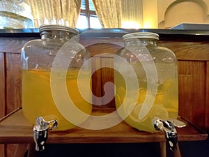 Set of two glass jars with faucets and drinks juices in a bar.