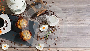Set of two muffins, cup of aroma coffee, jug of cream to coffee and candlestick on gray wooden background with copyspace.