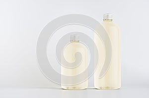 Set of two plastic tall and low bottles with pale fresh drink or cosmetic essential oil, silver cap mockup on white backgroundÑŽ