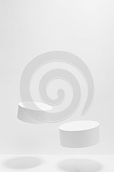 Set of two tilt round white podiums mockup for cosmetic products, levitate in hard light, shadow on white background.