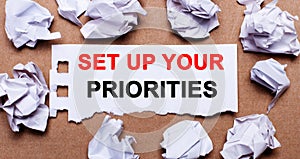 SET UP YOUR PRIORITIES written on white paper on a light brown background