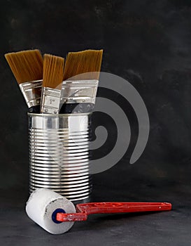 A set of used paint brushes in a tin can