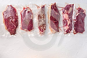 Set  of  vacuum packed organic raw beef alternative cuts: top blade, rump, picanha, chuck roll steaks, over white background, top