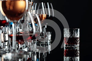 Set of various alcoholic beverages in glasses on a black reflective background