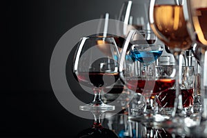 Set of various alcoholic beverages in glasses on a black reflective background