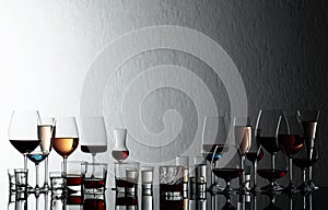 Set of various alcoholic beverages in glasses on a black reflective background
