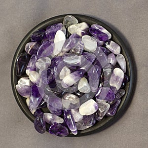 Set of various amethyst natural mineral stones and gemstones on grey linen and black plate background partial focused