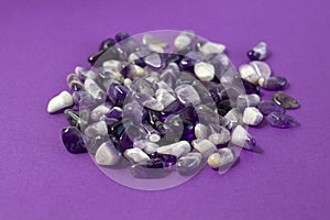 Set of various amethyst natural mineral stones and gemstones on purple background