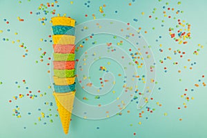 Set of various bright multicolored ice-cream waffle cones on blue background with scattered confetti sugar sprinkles