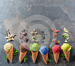 Set of various colorful ice creams in waffle cones with fruits slices on the grey background