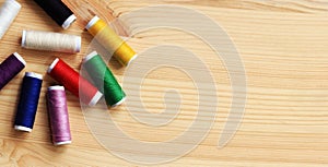 Set of various colorful sewing threads on a wooden table, close-up