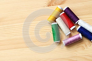 Set of various colorful sewing threads on a wooden table, close-up