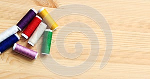 Set of various colorful sewing threads on a wooden table, close-up