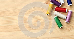 Set of various colorful sewing threads on a wooden table, close-up