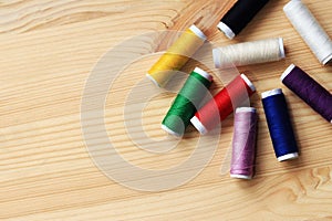 Set of various colorful sewing threads on a wooden table, close-up