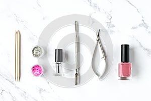 Set of various manicure and pedicure tools and accessories on white marble background.