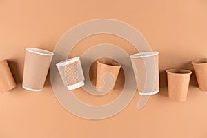 Set of various paper coffee cups over light brown background with copy space