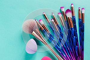 Set of various professional trendy fashion violet purple metallic makeup brushes on pastel green background. Flat lay, top view.
