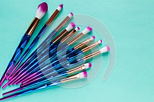 Set of various professional trendy fashion violet purple metallic makeup brushes on pastel green background. Flat lay, top view