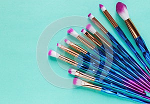 Set of various professional trendy fashion violet purple metallic makeup brushes on pastel green background. Flat lay, top view