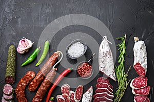 Set of various spanish dry cured salami sausages slices and whole cuts on balck background, flat lay with copy space