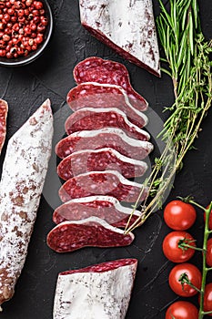 Set of various spanish dry cured salami sausages slices and whole cuts on black textured background