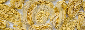 Set of various uncooked pasta on white wooden background, top view. From above, overhead. Closeup