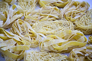 Set of various uncooked pasta on white wooden table, side view