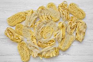 Set of various uncooked pasta on white wooden table, top view. From above, overhead