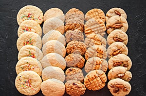 Set of variuos american style cookies on a black stone background. Shortbread, snickerdoodle, peanut butter, oatmeal and pecan co