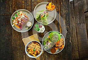 Set of vegetarian dishes on a wooden table top view. Pasta, green burger, falafel, shaurma