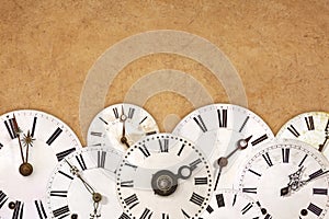Set of vintage white clock faces against an old brown background