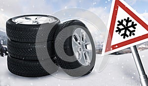 Set of wheels with winter tires on snow and road sign outdoors
