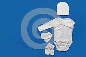 Set of white baby clothes on blue background.