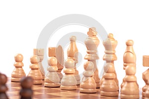 Set of white and black wooden chess pieces standing on a chessboard, isolated on white background