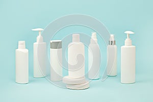 Set of white cosmetic bottles with soft shadows on light blue background. Home and beauty salon care concept, mock up, copy space