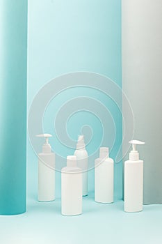 Set of white cosmetic bottles with soft shadows on light blue background. Home and beauty salon care concept, mock up, copy space