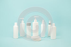 Set of white cosmetic bottles with soft shadows on light blue background. Home and beauty salon care concept, mock up, copy space