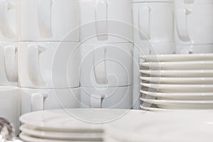 A set of white cups and plates are stacked for a banquet. Drinking coffee at conferences and business meetings. Close-up