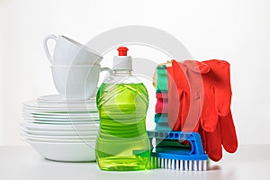 A set of white dishes and detergents on a white table.