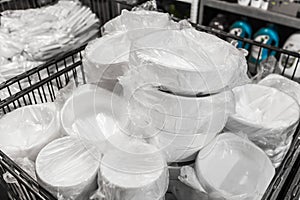 A set of white disposable plastic tableware in cellophane packaging in a store
