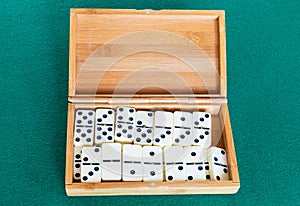 Set of white dominoes tiles in bamboo box on table